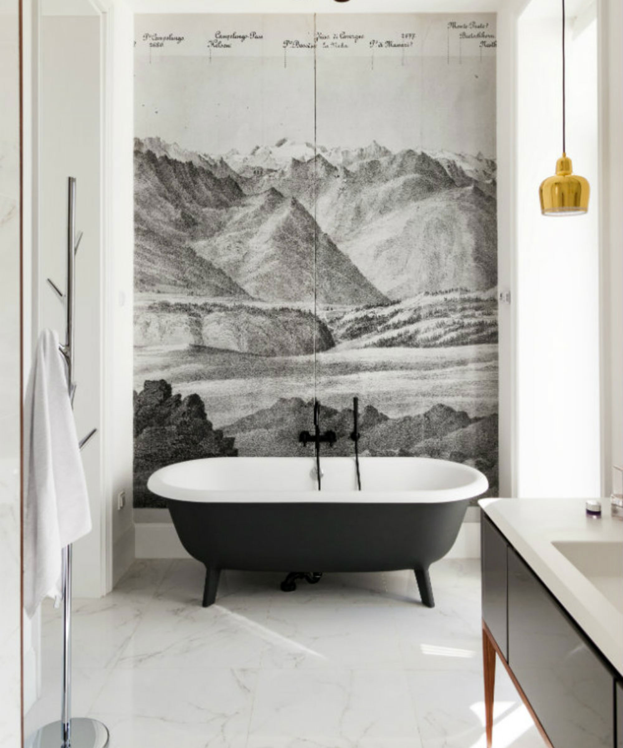 An example of grey bathroom ideas showing a grey wall mural behind a black free-standing bath