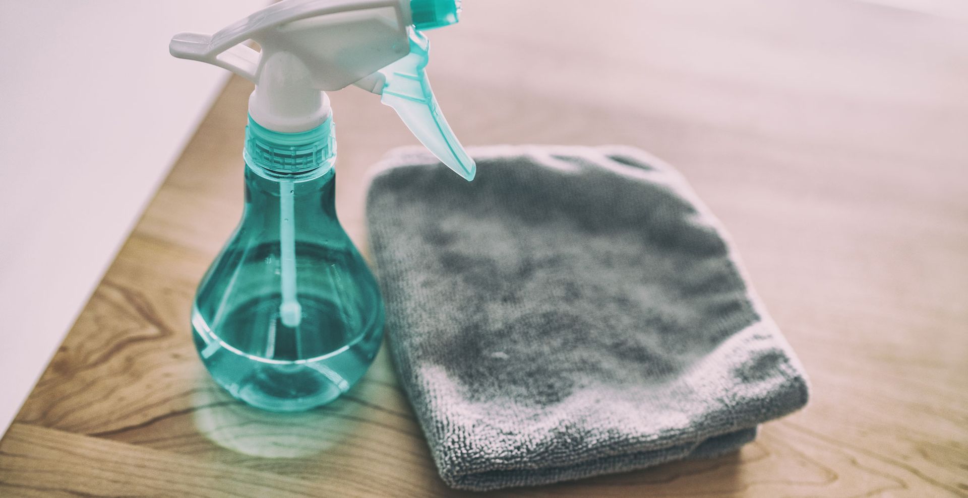 a microfiber cloth with a spray bottle on the table to show how to get rid of dust on surfaces in any room