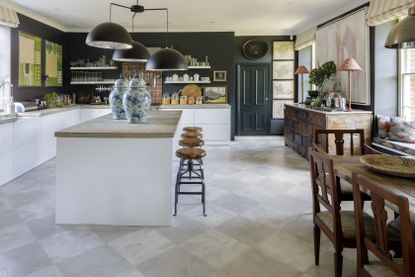 Large, modern kitchen with bright kitchen island, base cabinets, work surfaces and tiled flooring and contrasting grey/black painted walls 