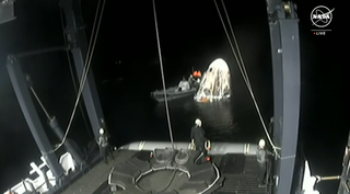 Recovery crews hook up the Dragon capsule to lift it from the sea off the coast of Pennsecola Florida