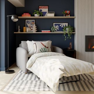 A grey chair bed with pull-out mattress in a living room with a dark blue wall