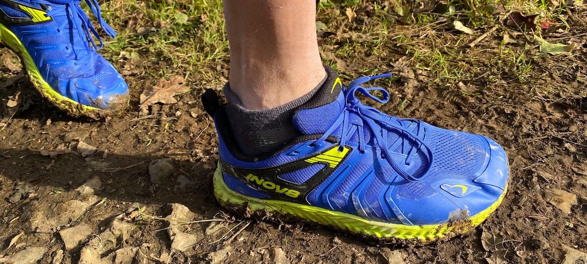 Closeup of Inov8 TrailTalon all-terrain running shoes being worn on muddy trail