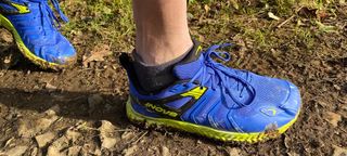 Close-up of Inov8 TrailTalon all-terrain running shoes being worn on muddy trail