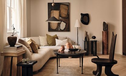 Beige living room with white curved corner sofa, black coffee table and armchair, brown abstract art and black pendant light