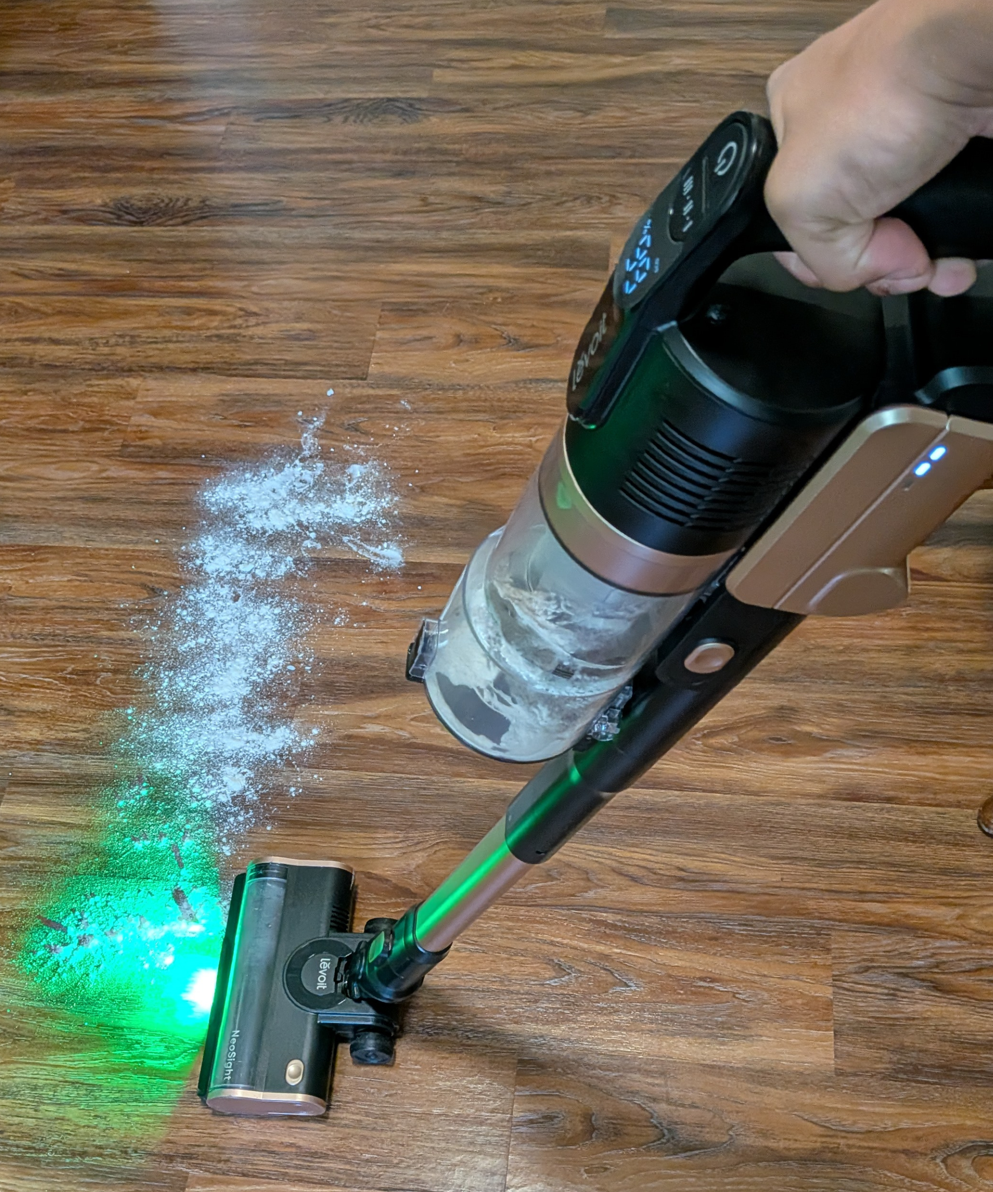 The Levoit VortexIQ Pro is using a green led light to illuminate flour particles on laminate flooring.