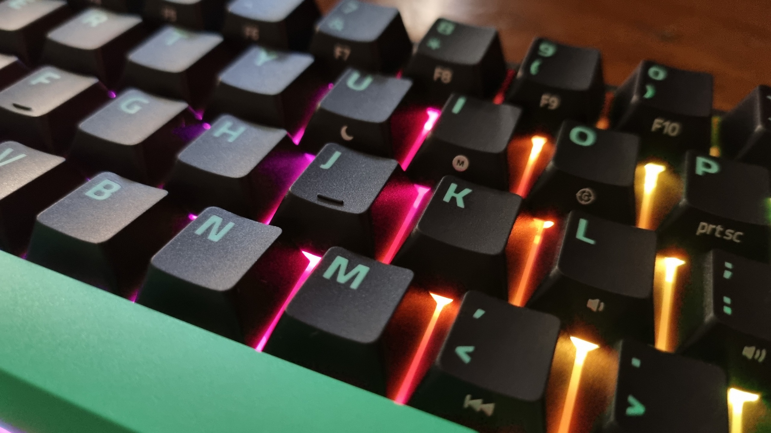 Close ups of the Razer Reclusa X Mini 65% gaming keyboard showing the RGB lighting effect
