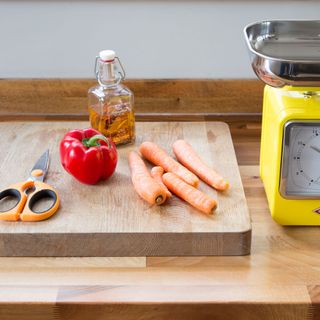 wooden chopping board with vegetables and oil and weight scale