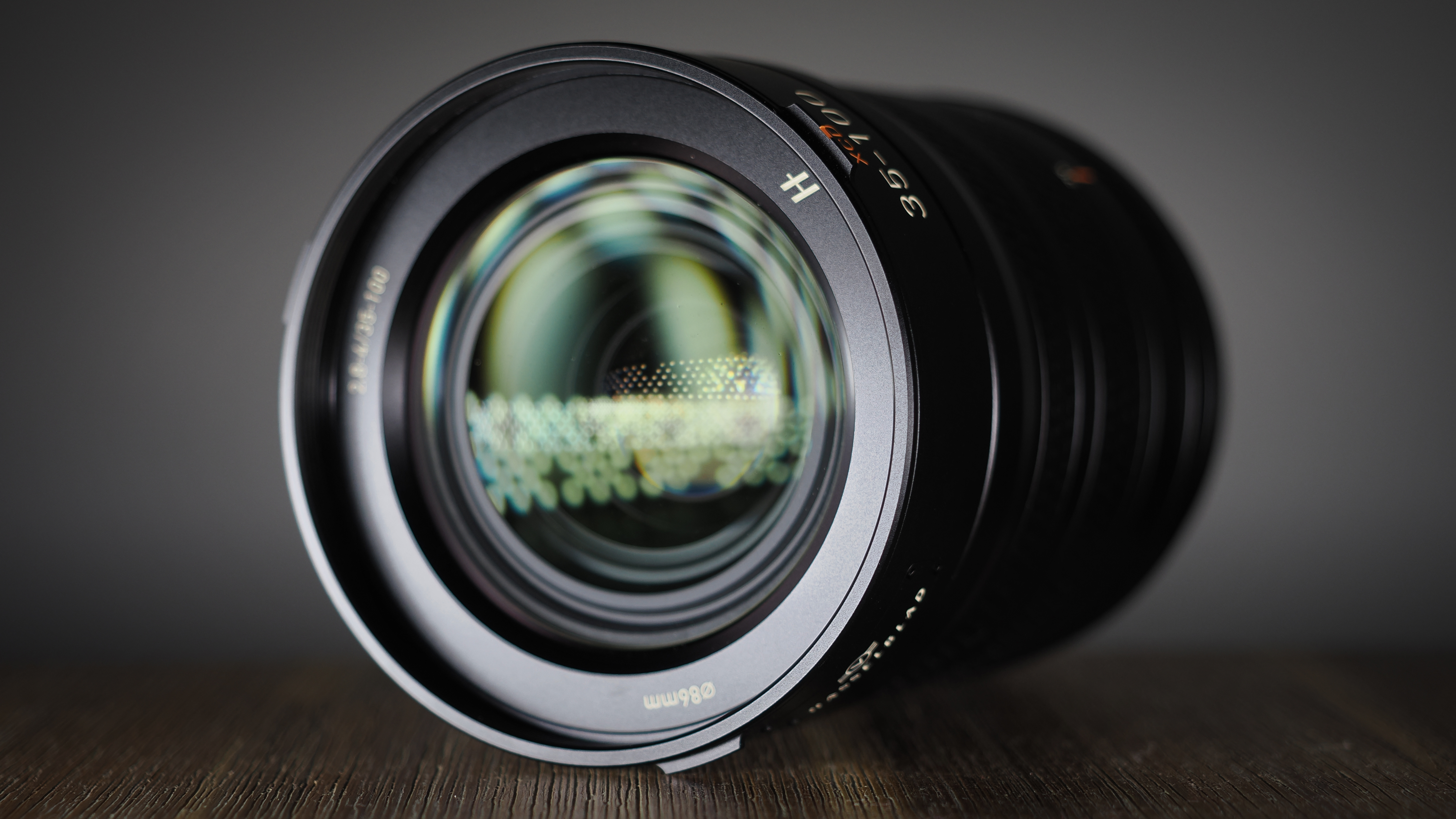 Hasselblad XCD 35-100E lens on a wooden surface in a moodily lit environment