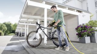 A pressure washer being used by a man to clean a bicycle