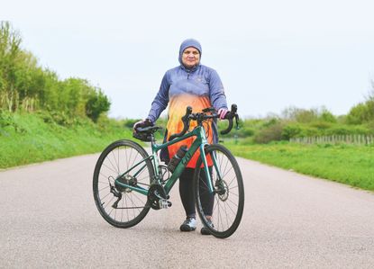 Iffat Tejani, wearing a modest cycling jersey, standing with her bike