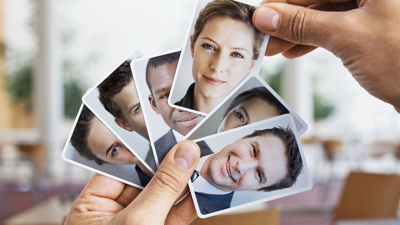 A man picks a woman&#039;s photo out of a group of photos he&#039;s holding.