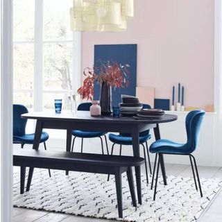 black dining table in room with rug, pink walls and dining chairs