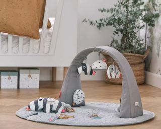 Done by Deer Activity Gym in a baby's room with a wooden floor and a white cot