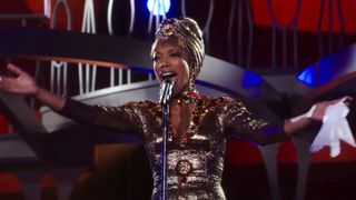 Naomi Ackie as Whitney Houston singing in a gold dress in I Wanna Dance with Somebody