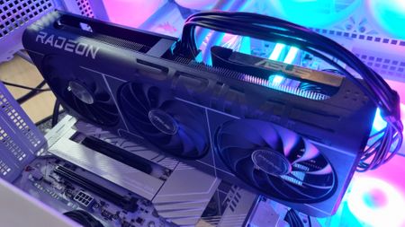 An Asus Prime Radeon RX 9060 XT 8 GB graphics card in a test PC with bright RGB lights in the background