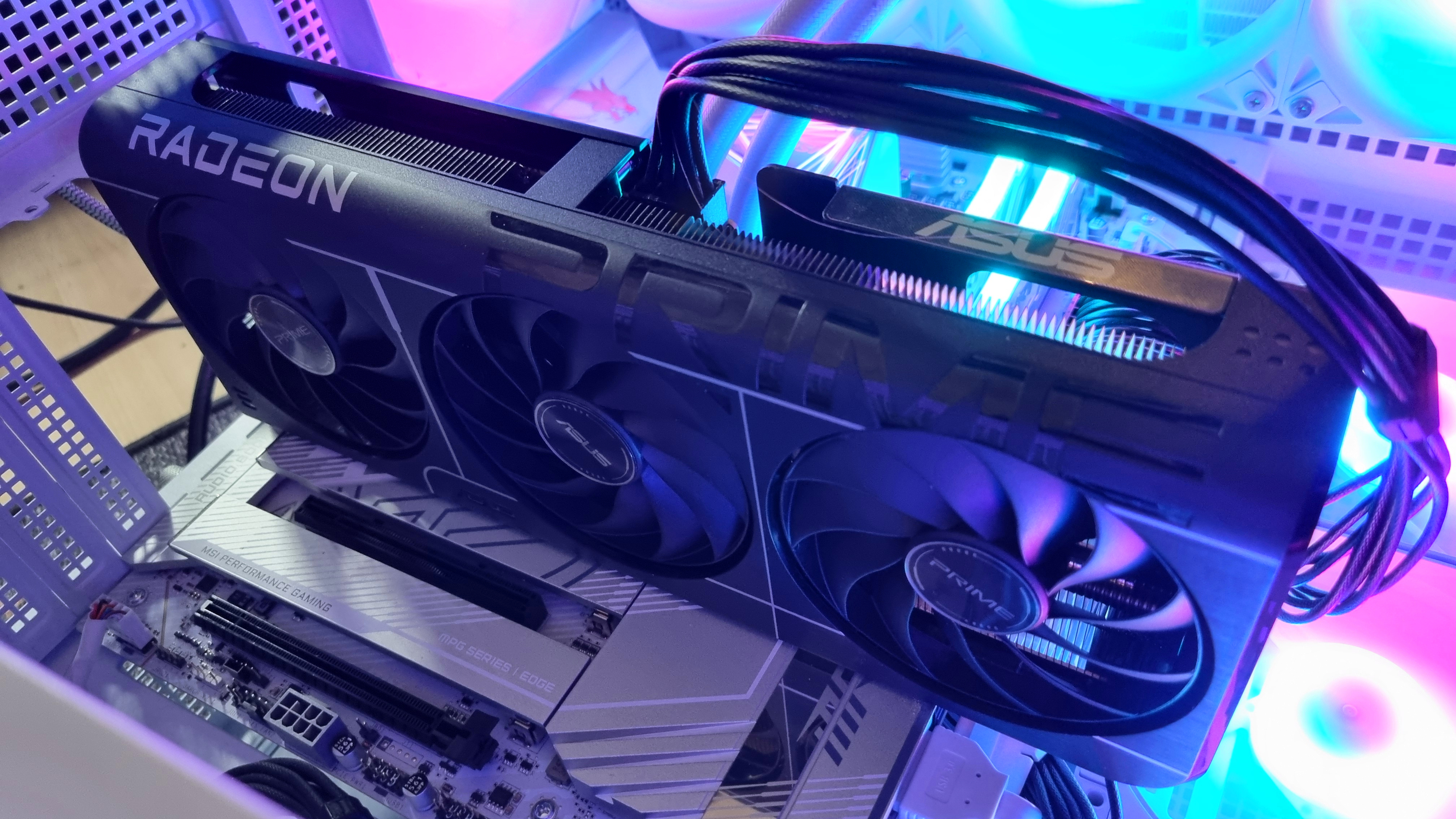 An Asus Prime Radeon RX 9060 XT 8 GB graphics card in a test PC with bright RGB lights in the background