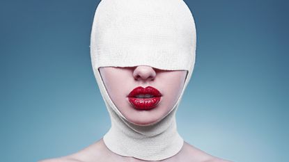 Portrait of young fashion woman with bandaged head wearing red lipstick on bright background