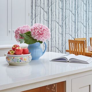 A kitchen island with a vase of flowers and a fruit bowl