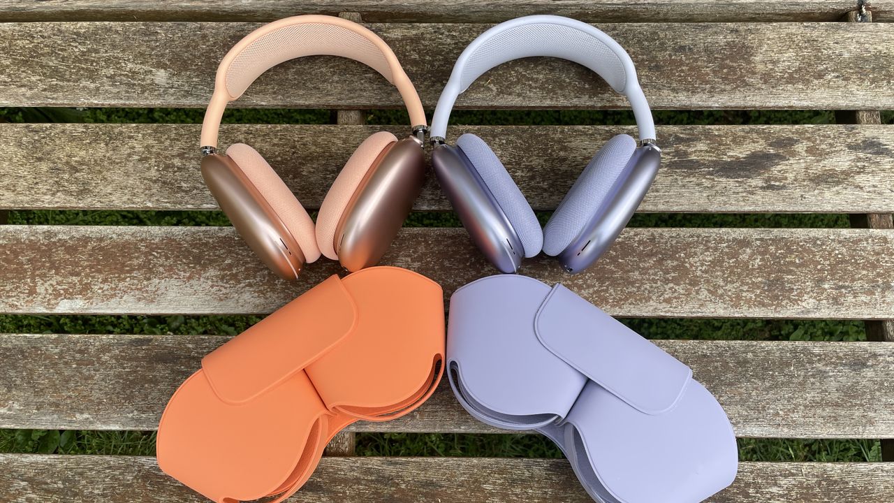 Apple AirPods Max 2 in orange with AirPods Max just visible in purple, outside in a garden on a bench, held in a hand