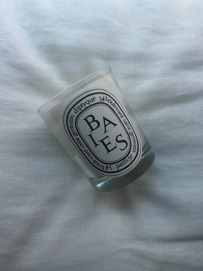 The Diptyque Baies candle on a white linen background