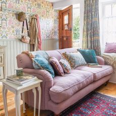 Small combined living room and hallway, with panelled walls, patterned wallpaper and curtains and pink sofa