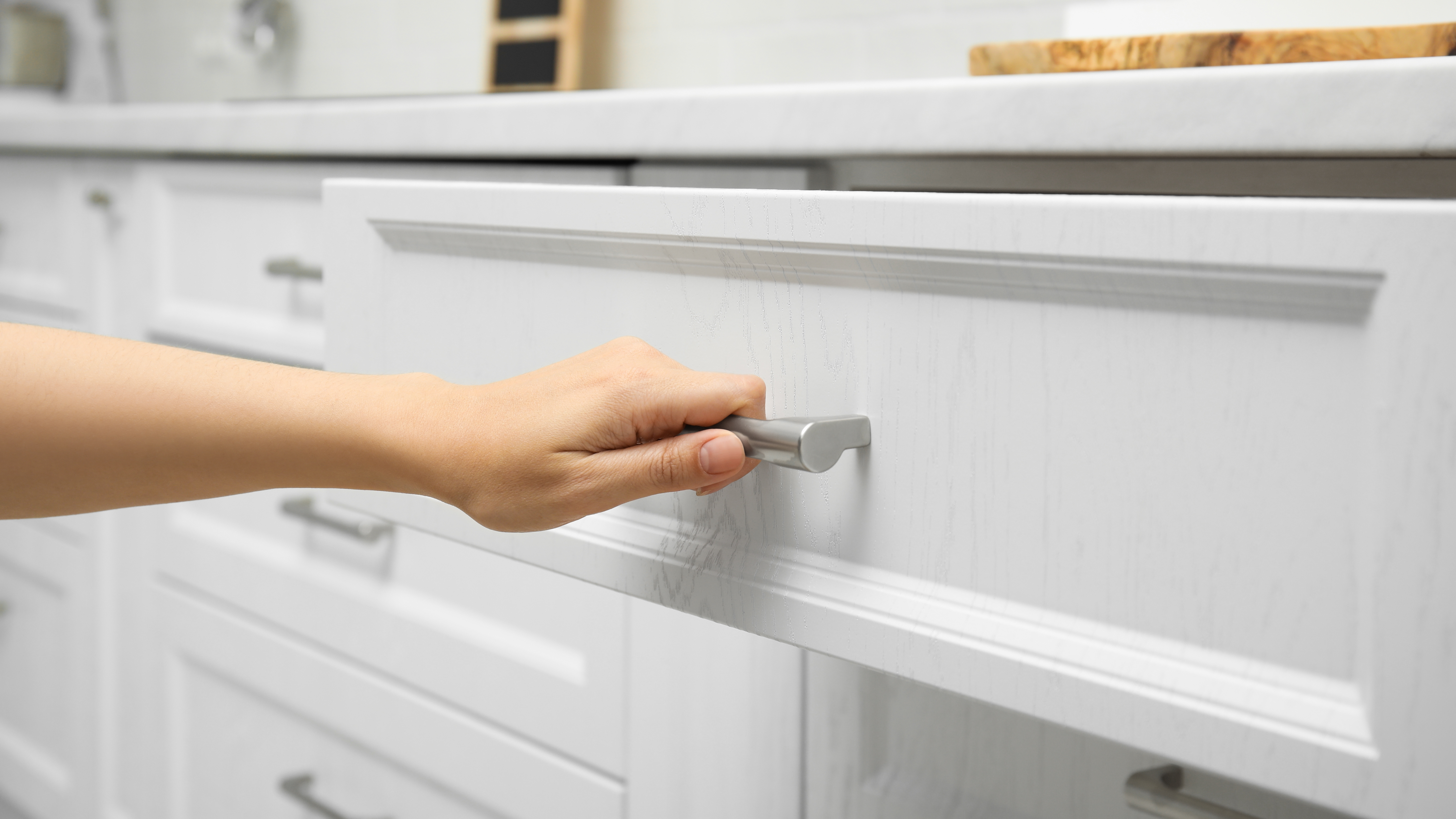 Hand pulling out a white kitchen drawer