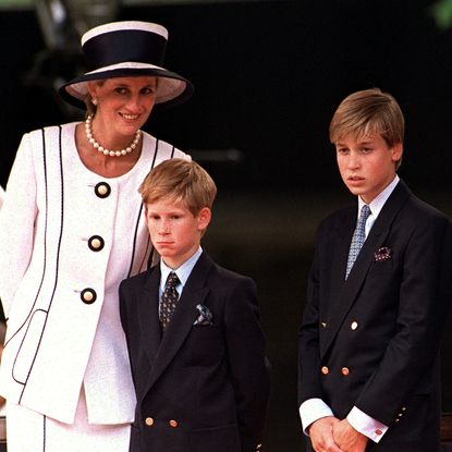 Princess Diana wears a white suit and matching hat with black piping, and poses with her sons Prince Harry and Prince William