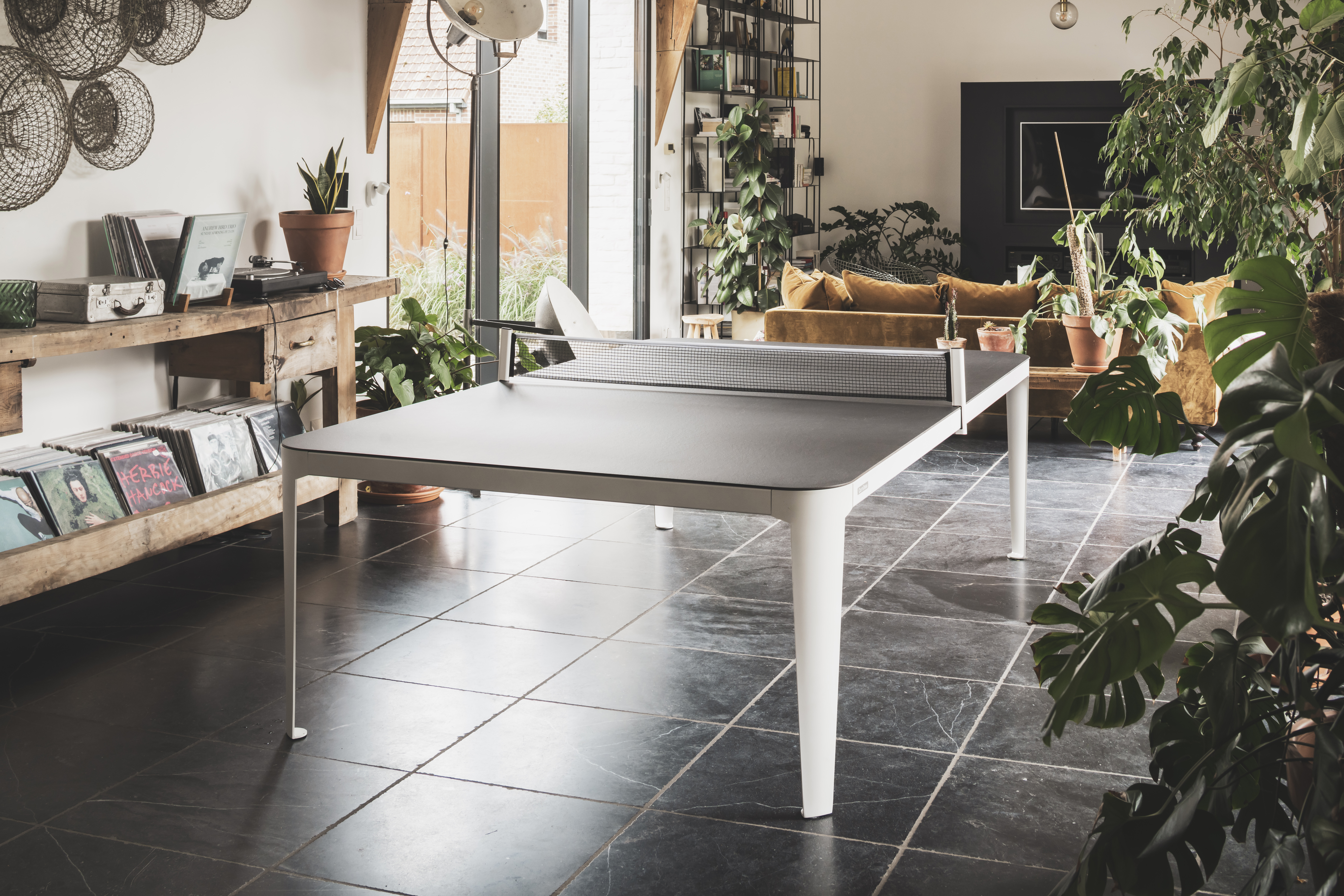 an image of a Cornilleau table tennis table in white, set up for a game indoors, in an open plan living room