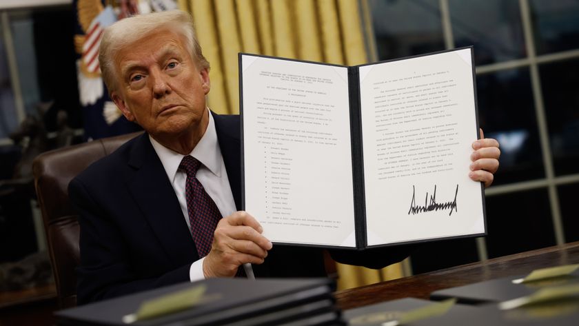 President Donald Trump holds up an executive order.