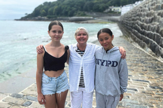 A woman standing beside two pre-teen girls