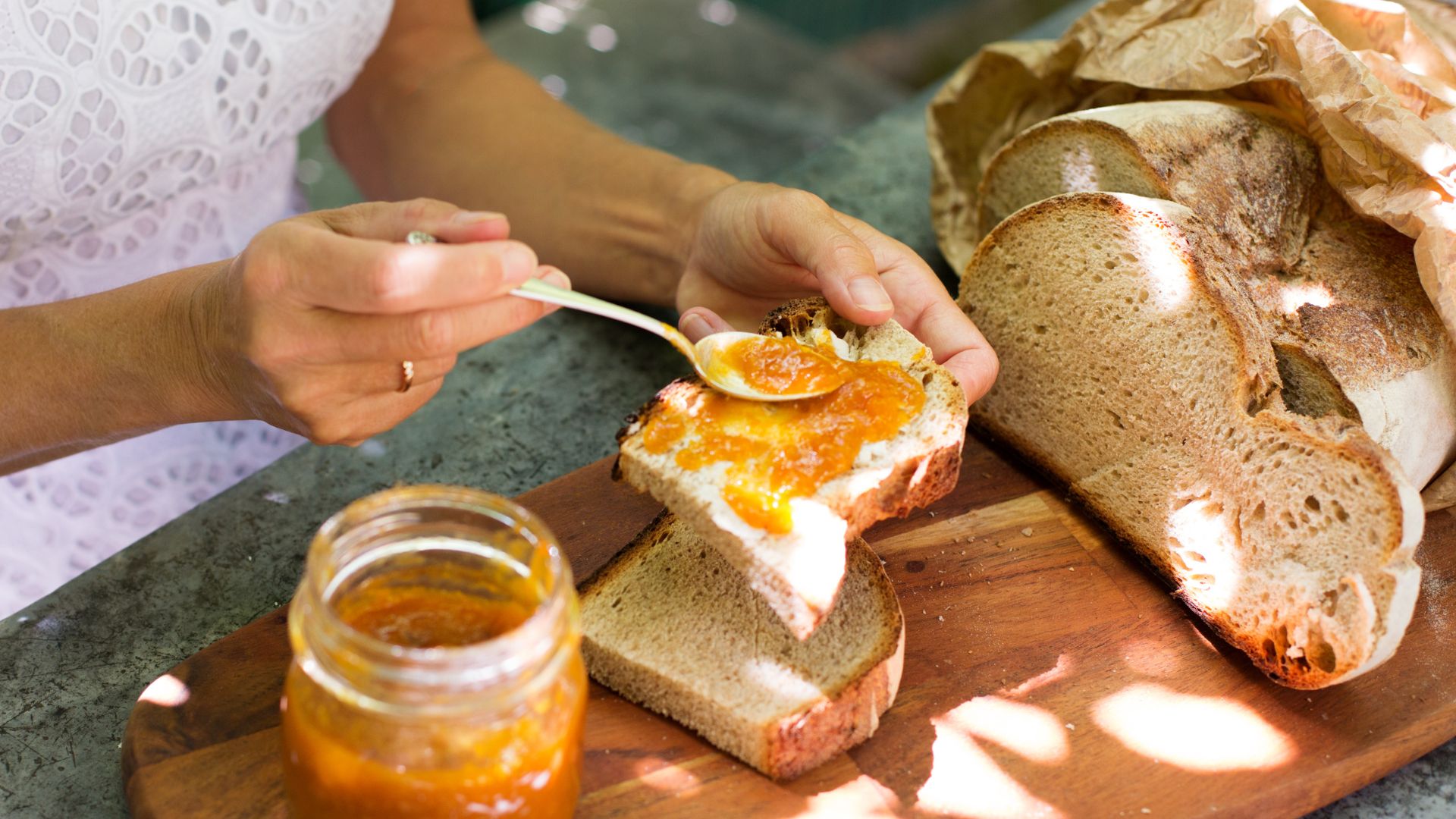 Sourdough on wooden board with orange jam on spoon