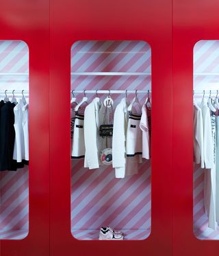 White toned clothing on rail inside red wardrobe