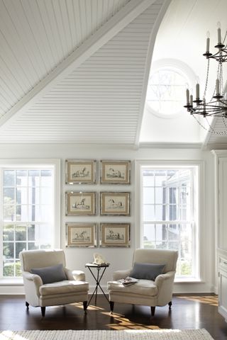 white living room with two armchairs and shiplap ceiling painted white
