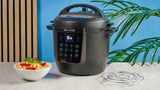 a black pressure cooker photographed against a blue background, showing its cooking presets, steam release valve, and Instant Pot branding