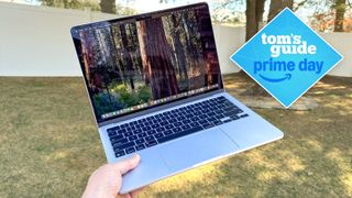 MacBook Air M4 held in hand in outside garden with Tom's Guide Prime Day badge