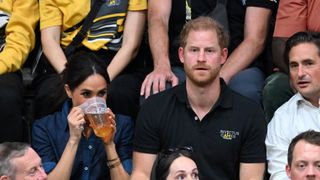 Meghan Markle drinking beer in the crowd next to Prince Harry