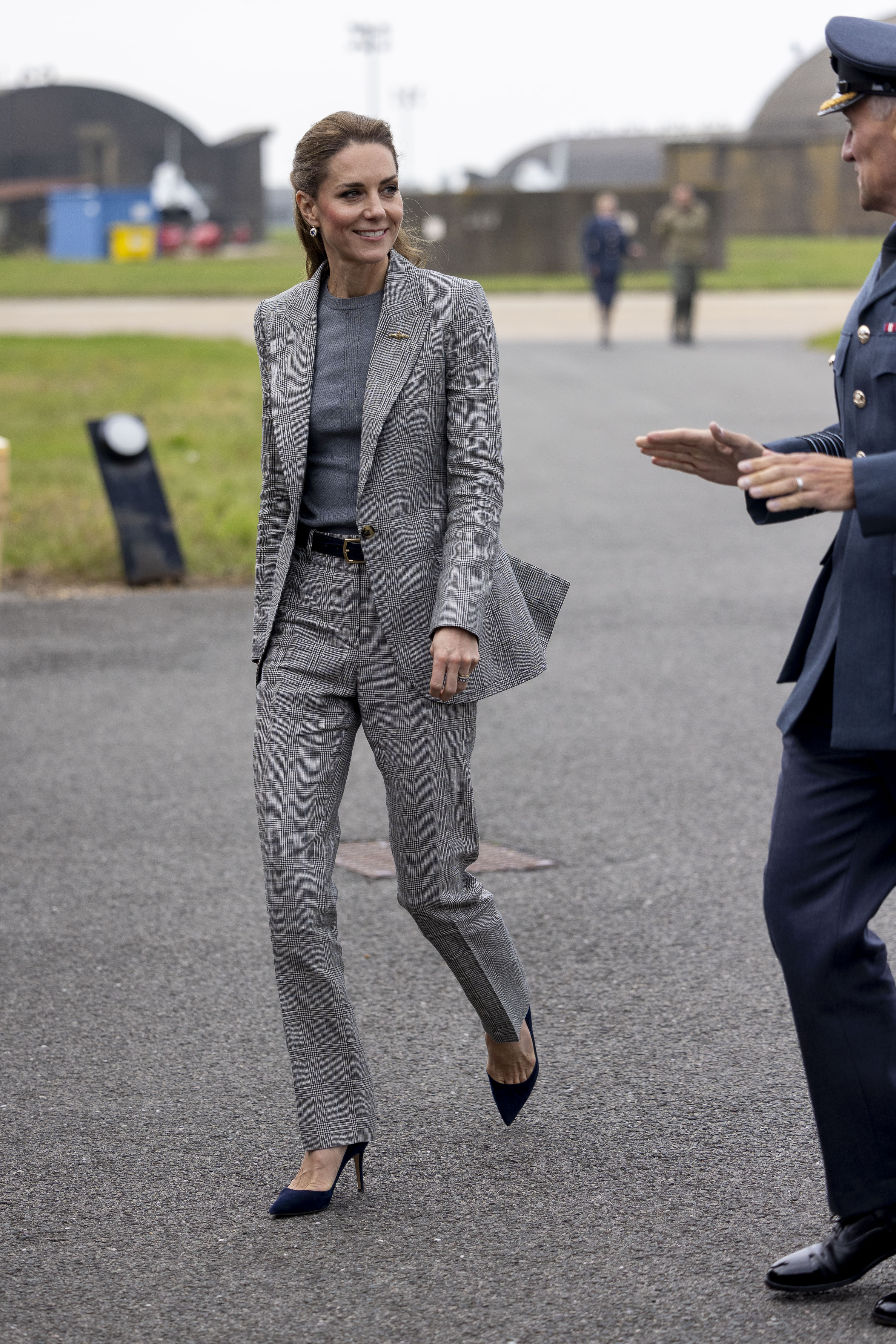 Kate Middleton wearing a gray suit walking next to a man on an air force base