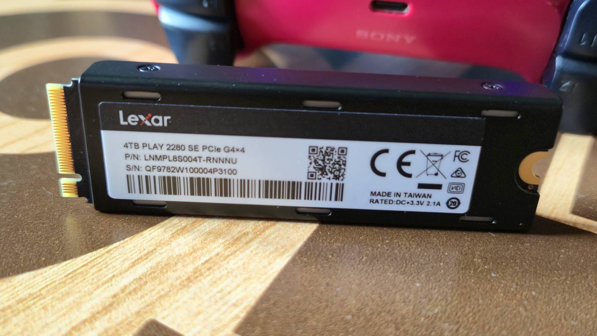 Photo by Rosalie Newcombe of the back of the Lexar Play 2280 SE PS5 SSD, sitting on a wooden table.