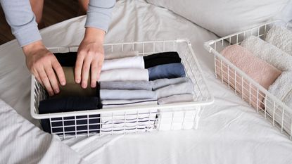 White baskets of clothes on bed