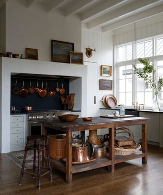 Modern farmhouse kitchen with high ceilings, a traditional range cooker and hanging copper pans
