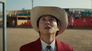 Steven Yeun as Ricky "Jupe" Park looking up at the sky during the sci-fi movie, Nope.