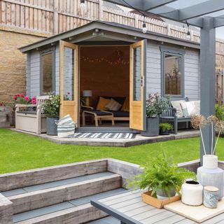 garden with summerhouse with doors open to reveal a sofa and Ikea rocking chair