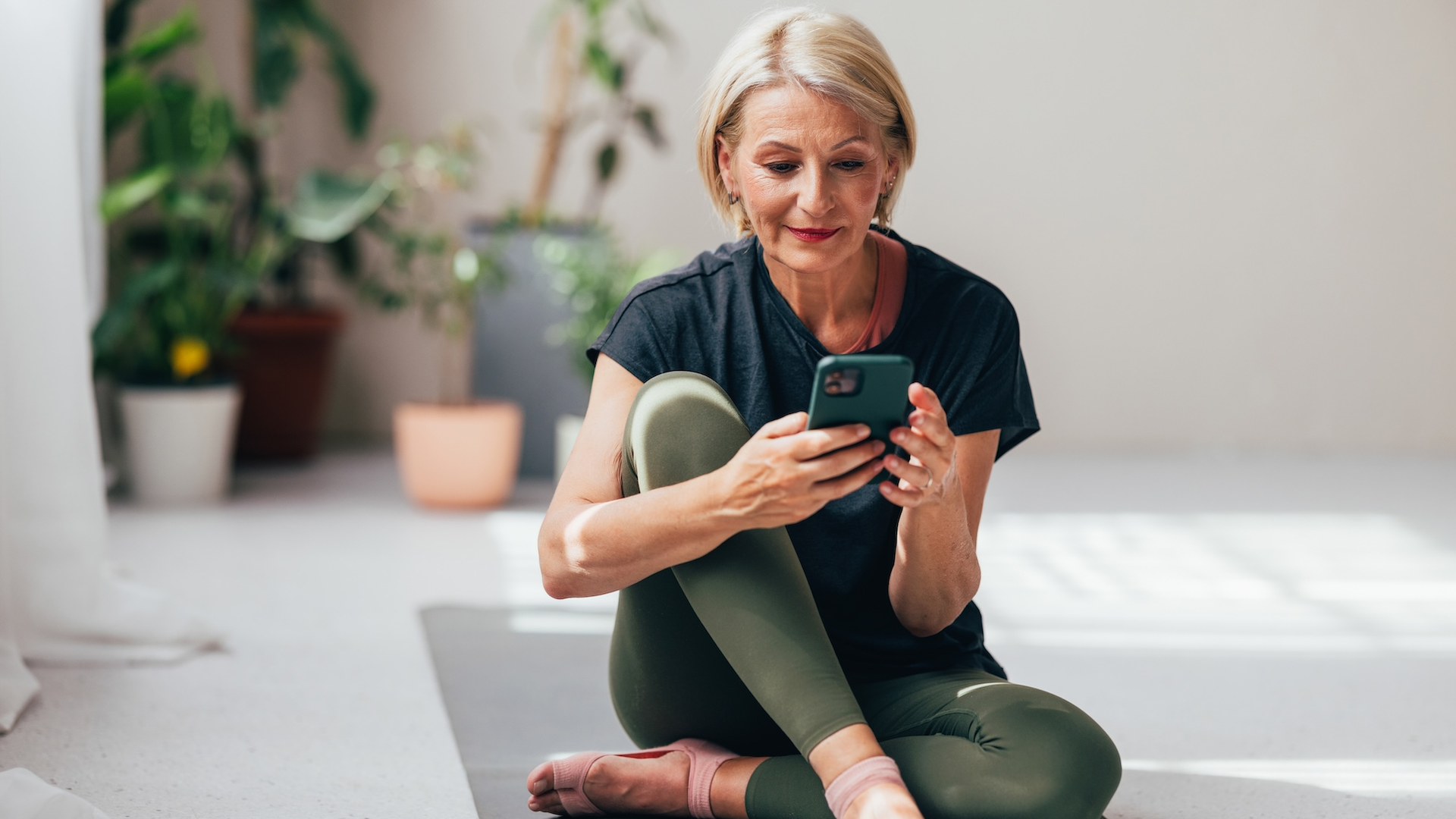 Woman looking at phone on yoga mat