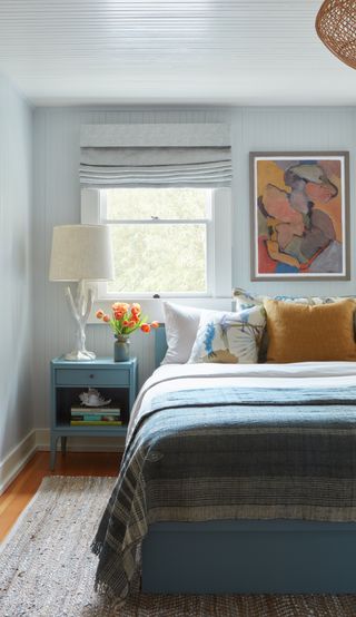 A small bedroom with a light blue paint on walls and ceiling