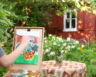 child painting on easel in garden