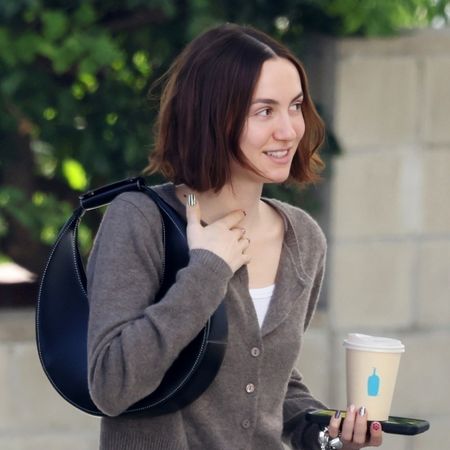 Maude Apatow wearing a brown Reformation cardigan, jeans, and black sneakers