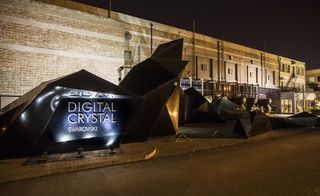 Large brick building with a black, angular structure displaying "Digital Crystal Swarovski"