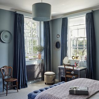 Classic bedroom with floor length curtains and blue colour scheme
