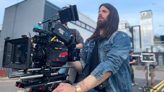 Cinematographer Andrew Roger using a large cine camera on a film set