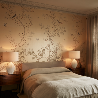 a bedroom with matching bedside lights on each side of a double bed and chinoiserie wallpaper behind